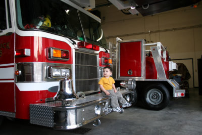 Curious Boy Sitting On A Fire Truck